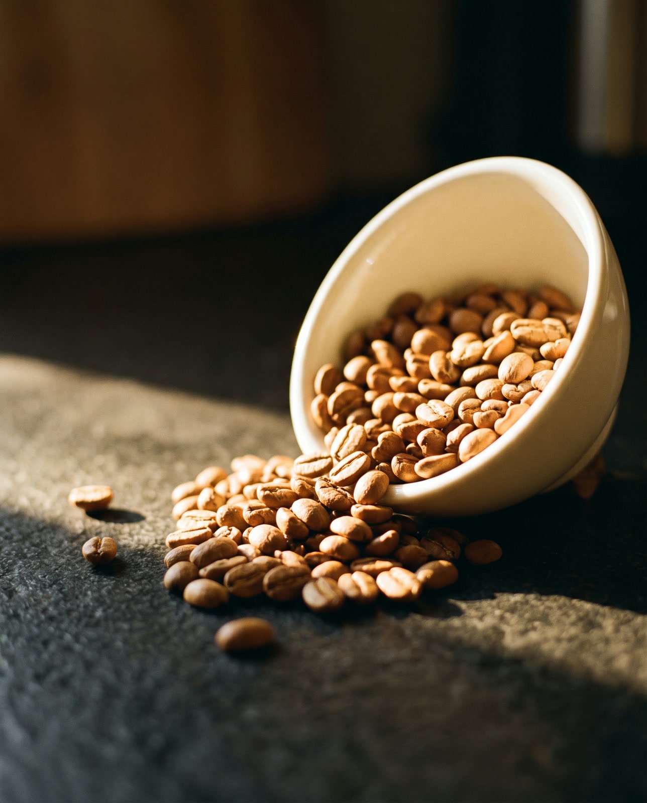 Light golden roasted beans spilling from a cream bowl in warm morning light